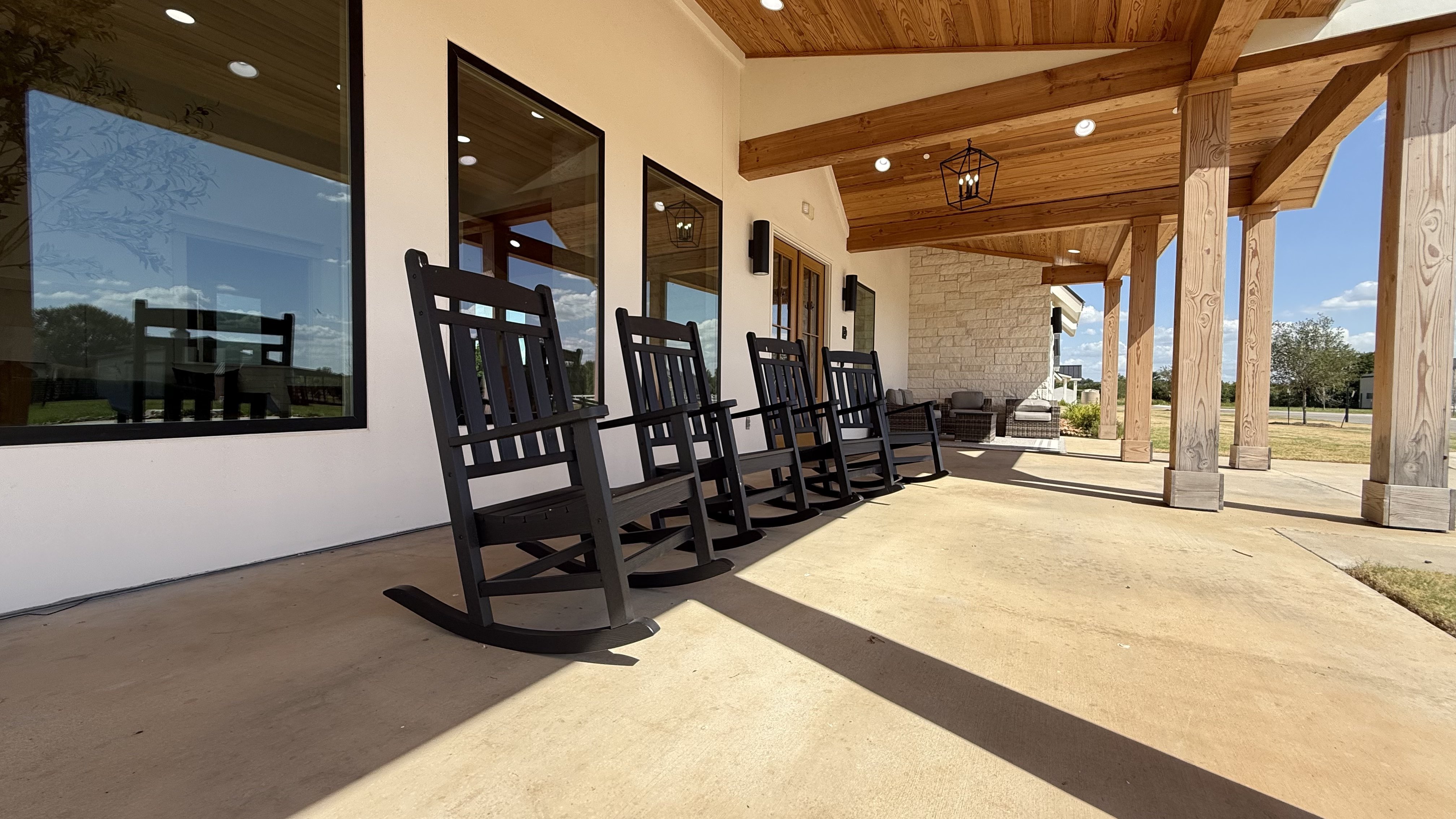 Covered front porch at The Valencia with rocking chairs and warm wood-beam ceiling